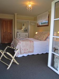基督城Magnolia Cottage的一间卧室配有一张床和一把椅子