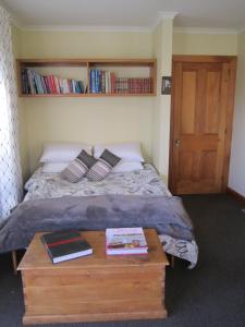 基督城Magnolia Cottage的一间卧室配有一张床和一张桌子及书籍