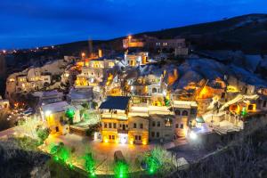 AyvalıCappadocia Gamirasu Cave Hotel的一群晚上在山丘上的房子