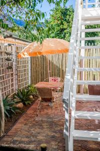 斯泰伦博斯Cobie Apartment的庭院配有橙色雨伞和带梯子的桌子