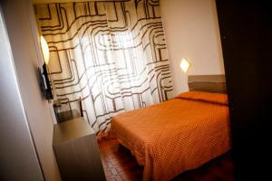 都灵吉亚塔酒店的一间卧室配有橙色的床和窗户。