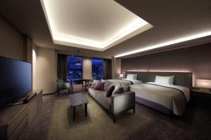 仙台仙台东大都会酒店 的一间卧室配有一张床、一台电视和一张沙发
