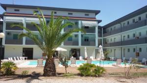 普林希匹纳马尔Residence Verde Pineta的一座建筑前有棕榈树的酒店