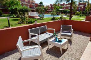 马尔德·克里斯塔尔Albatros Playa 2 - 9408的庭院设有三把椅子和一张桌子,庭院内设有游泳池