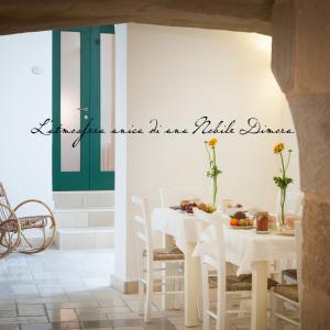 米内尔维诺迪莱切B&B Donnantonietta - Nobile dimora的一间设有白色桌子和白色椅子的用餐室