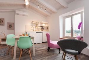 罗维尼Apartments and Rooms Hey Rovinj的厨房以及带粉色和绿色椅子的用餐室。