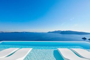 伊亚Canaves Oia Suites - Small Luxury Hotels of the World的一个带白色椅子的游泳池,享有海景
