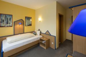 加尔布森格罗特尔商务酒店的一间卧室配有一张床,床头柜配有蓝灯