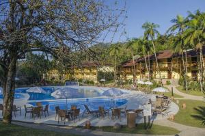 南雅拉瓜Hotel Fazenda Vale das Pedras的一个带椅子和遮阳伞的游泳池的度假酒店