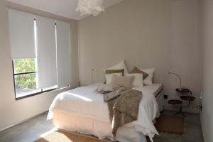 科洛尼亚-德尔萨克拉门托Las Glicinas Boutique Apartments的白色卧室配有带枕头的床和窗户