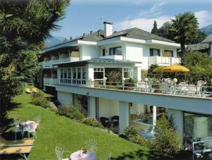 梅拉诺安娜贝尔酒店的一座大白色房子,在山坡上配有桌椅