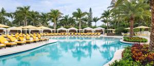 迈阿密Trump National Doral Golf Resort的度假村的游泳池配有椅子和遮阳伞