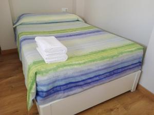塔里法Apartamento Pura Vida的一张带彩色床单和毛巾的小床