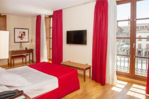卡塞雷斯唐费尔南多索霍精品酒店的一间卧室配有红色窗帘和一张带电视的床