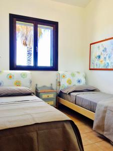 普尔萨诺Villa Lido Silvana Marina di Pulsano的一间卧室设有两张床和窗户。