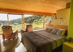 塔卡卡Golden Bay Hideaway的一间卧室配有一张床和两把椅子,并设有一个大窗户