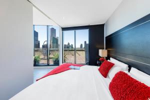 墨尔本弗林德斯灵气公寓的卧室配有带红色枕头的大型白色床