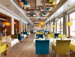 佩尔蒂绍Hotel der Wiesenhof的餐厅设有白色的桌子和蓝色的椅子以及窗户。