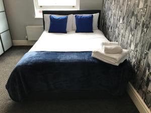 伯明翰Haya Guest House的一张大床,上面有蓝色的枕头和毛巾