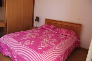 普拉亚Apartamento António的一张带粉红色床罩和枕头的床