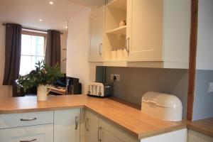 赖厄德Delfryn Cottage的厨房配有白色橱柜和台面