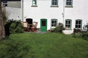 赖厄德Delfryn Cottage的一座房子,配有两把椅子和一扇绿门