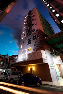 Kuala Belait瑞士公寓酒店的一座高大的建筑,前面有汽车停放