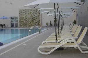 科托努迪帕美特金郁金香酒店的游泳池旁一排带遮阳伞的躺椅
