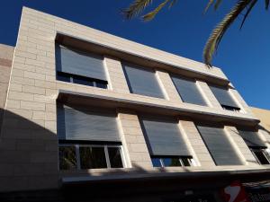 阿里纳加Viva Cruce de Arinaga的一座带百叶窗和棕榈树的建筑