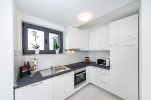 扎顿Apartments Menalo的白色的厨房配有白色橱柜和水槽