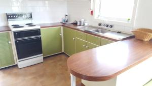 马奇Kaylee Cottage Mudgee的厨房配有绿色橱柜和木桌