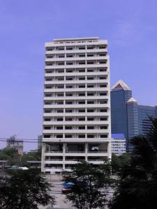 曼谷蓬乔克公馆酒店的一座高大的白色建筑,在城市前方有树木