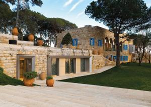Beit Meri阿尔布斯坦酒店的一座带蓝色窗户和庭院的石头房子