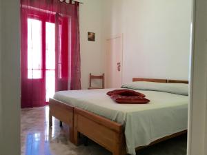 马蒂诺Casa nel Salento da Grace的一间卧室配有床和红色窗帘的窗户