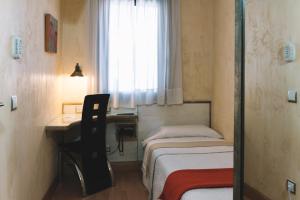 潘普洛纳卡斯蒂略哈维尔酒店的小房间设有两张床、一张桌子和一个窗口