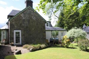 圣菲伦斯Glenalbyn Cottage的一座古老的石头房子,前面设有一个花园