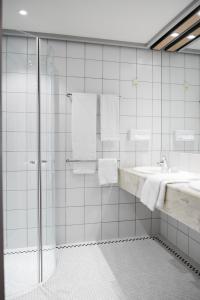 瓦埃勒瓦埃勒中心酒店的带淋浴和盥洗盆的白色瓷砖浴室