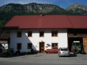 纳瑟尔文勒Haus Walter的一座白色的建筑,有红色的屋顶,前面有停车位
