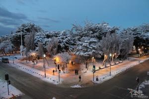蓬塔阿雷纳斯广场酒店的夜间有雪覆盖的公园,人们在步行