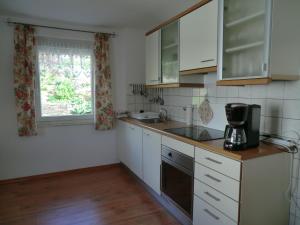 PolleFerienwohnung Kehmeier的厨房配有白色橱柜、水槽和窗户。