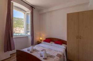 科米扎Apartment Riva 5的一间卧室配有一张带红色枕头的床和一扇窗户