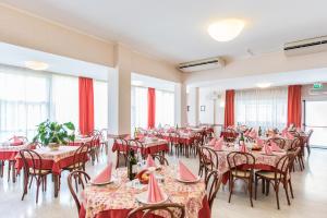里米尼Hotel Seven的一间带桌椅和红色窗帘的餐厅