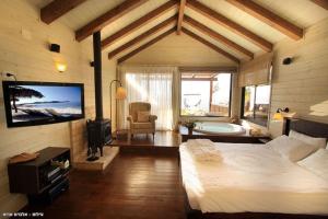 玛尔盖姆拉green island的一间卧室配有一张床、一台电视和一个浴缸