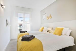 萨拉戈萨Mirador del Ebro的黄色和白色的客房内的两张床