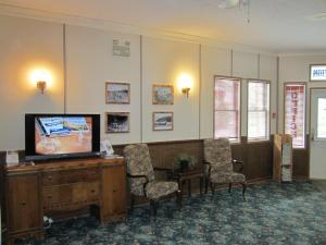 道森市Triple J Hotel的一间配有平面电视和椅子的等候室