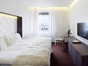 哥德堡世界酒店的卧室配有一张白色大床、一张桌子和一台电视机。