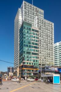 釜山艾丽西亚精品酒店的前面有汽车的一座高大的玻璃建筑