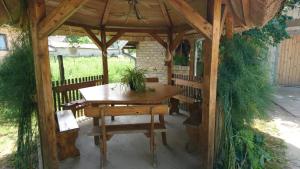 GajićApartment Kostolic的木制凉亭配有木桌和长凳