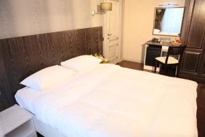 阿拉木图D'拉米酒店的卧室配有一张白色大床和一张书桌