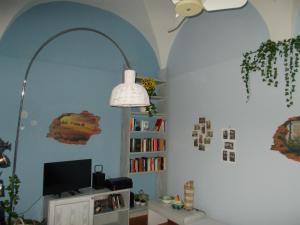 卡萨莱蒙费拉托“La Loggia” Apartment的一间配有电视的房间和书架